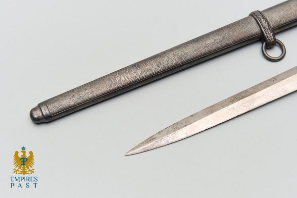 Antique dagger with a textured metal sheath and a ring-hilt, blade laid beside the scabbard; blue Empires Past logo bottom left.