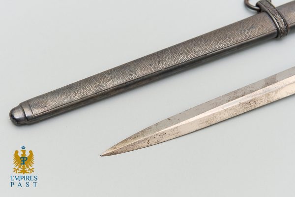 Antique dagger with textured metal sheath and a long, polished blade; Empries Past logo visible in corner.