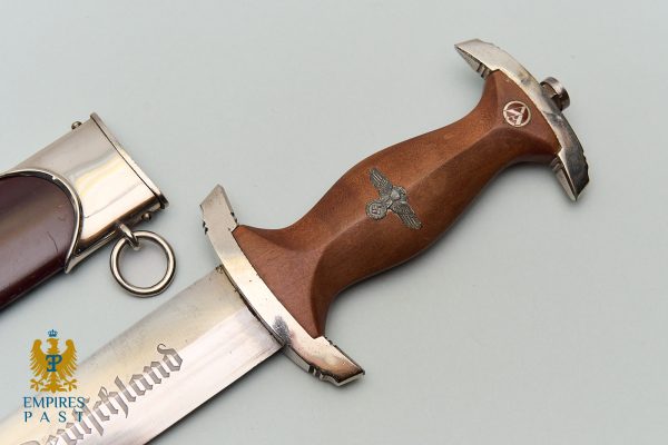 Nazi-era dagger with brown wooden grip and swastika eagle insignia; blade partially visible, with Empires Past watermark in the corner.