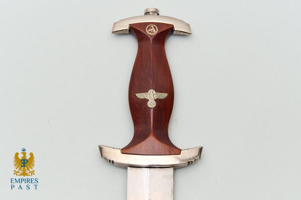 Wooden-hilt dagger with metal fittings and Nazi eagle insignia on the grip against a pale background.