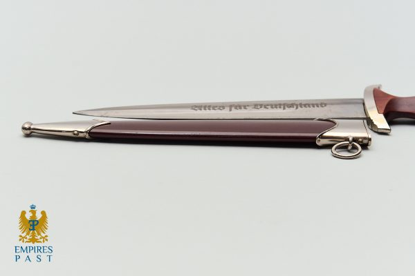 Ceremonial dagger with a burgundy sheath and metal fittings on a white background; Empire's Past logo in the lower-left corner.