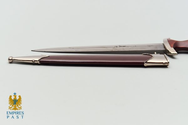 Antique dagger laid flat on a light surface, brown handle with silver fittings and a long blade; Empires Past logo bottom left.
