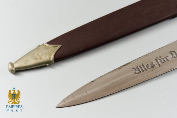 Antique dagger with brass hilt and brown leather sheath; Gothic script on blade; Empires Past logo in the corner.