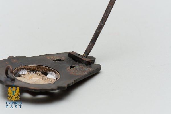 Close-up of a rusty, broken metal lock plate with a bent lever extending from it, showing corrosion and wear.