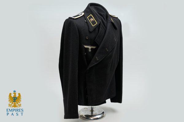 Black WWII German officer coat on a mannequin, featuring gold-trim shoulder boards and eagle insignia, displayed against a pale backdrop with a logo in the bottom-left corner.
