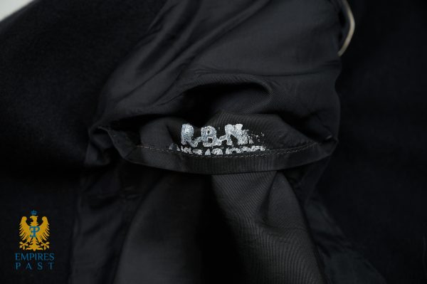 Close-up of black jacket fabric with a small white distressed logo along a seam; Empires Past crest visible in the bottom-left corner.