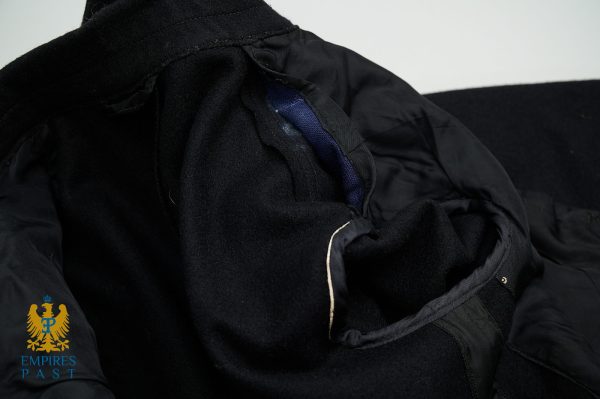 Close-up of a black coat’s lining and seam, with a blue edge showing, and the Empires Past logo in the bottom-left corner.