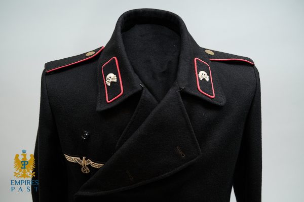 Black military coat on a mannequin with red-edged shoulder boards featuring skull insignia and a gold eagle emblem at chest level. Empire Past watermark visible.