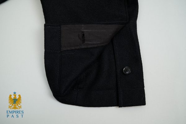 Close-up of a black coat sleeve cuff with a stitched pocket and button, logo watermark in the bottom-left corner reading 'Empires Past'