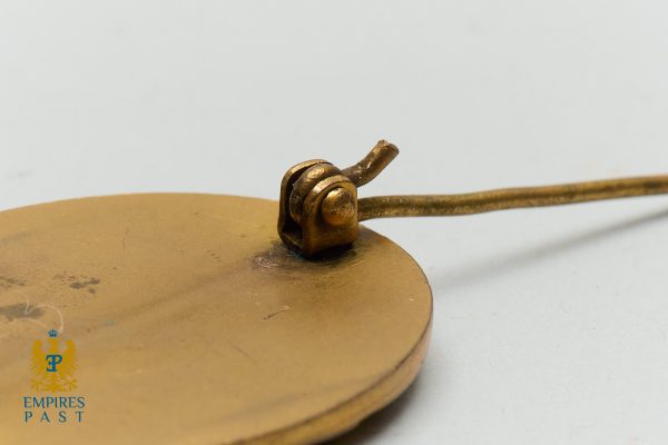 Empires Past 202517295 - Empires Past Close-up of a brass hinge on a round brass disc with a thin rod extending to the right.