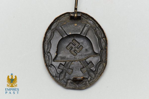 Empires Past 202517360 - Empires Past Oval metal pendant with a raised helmet motif and swastika, hanging from a loop (WWII German insignia).