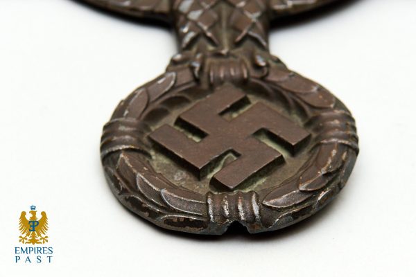 Bronze pendant with a laurel wreath surrounding a central swastika on a white background; Empires Past logo in the lower-left corner.