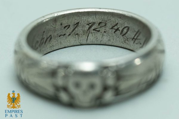 Close-up of a silver ring's inner circumference showing a scratched engraved inscription.