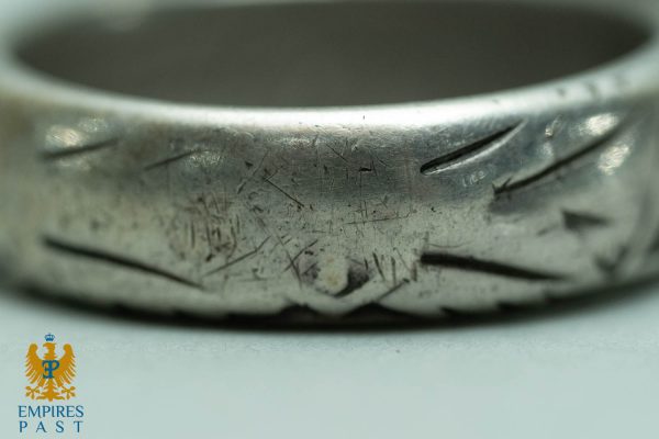 Close-up of a scratched silver ring with many surface cuts.