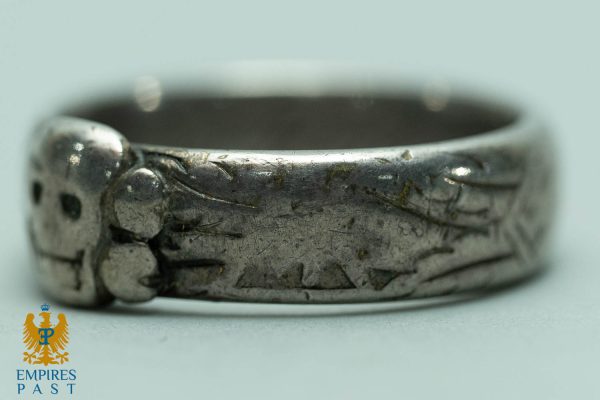 Close-up of a worn silver ring with engraved patterns along the band.