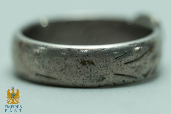 Close-up of a worn silver ring with scratches and a matte finish; Empires Past logo is in the bottom-left corner.