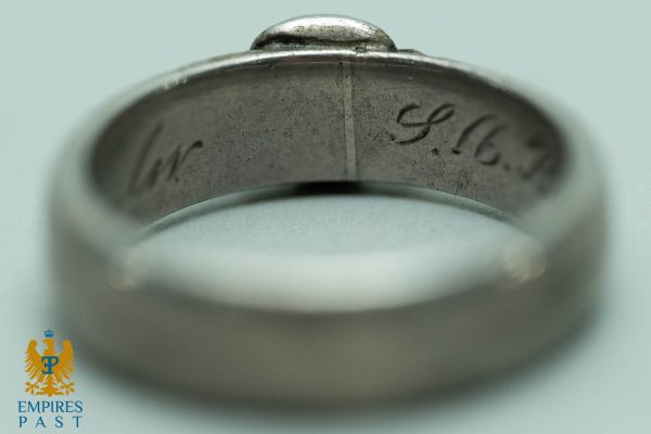 Close-up of a metal ring's inner band with a worn engraved inscription along the inside edge.