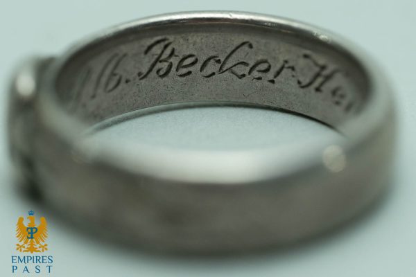 Close-up of a metal ring's inner band with delicate cursive engraving (macro shot).